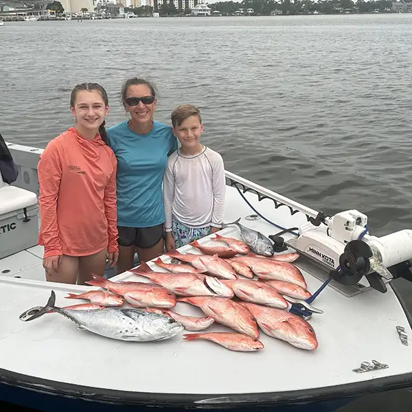 Family on a bay charter boat with a fresh catch of red snapper and nearshore species